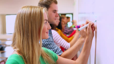 Row-of-students-writing-on-whiteboard-in-classroom