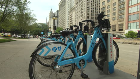editorial, chicago public bike share diyy, divvy station, blue bicycles, street view, people and cars passing.