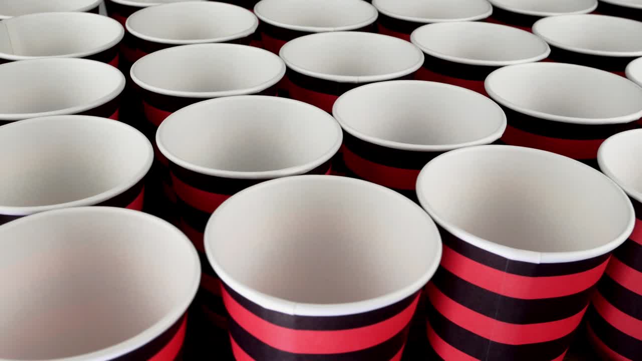 어두운 배경에서 커피 또는 뜨거운 음료를위한 빨간색과 검은색 일회용 종이 컵을 천천히 회전하십시오.