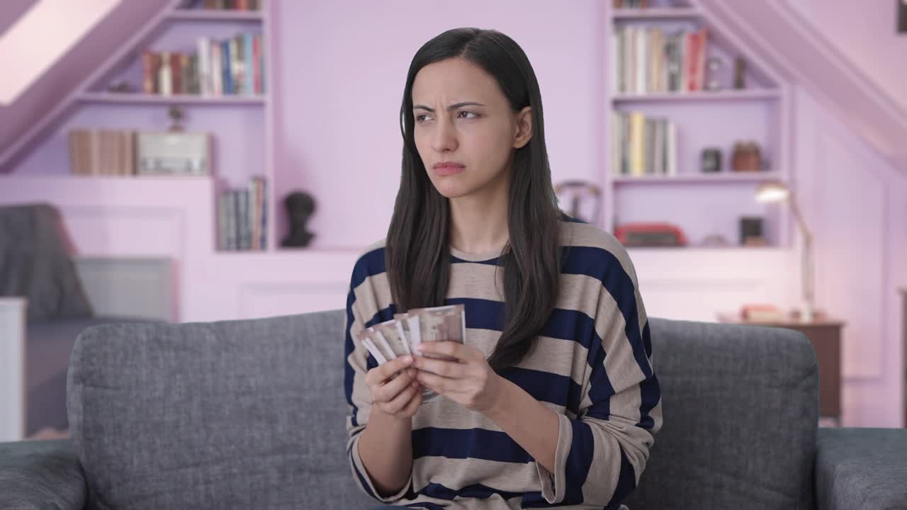 Ragazza indiana triste che perde soldi mentre li conta
