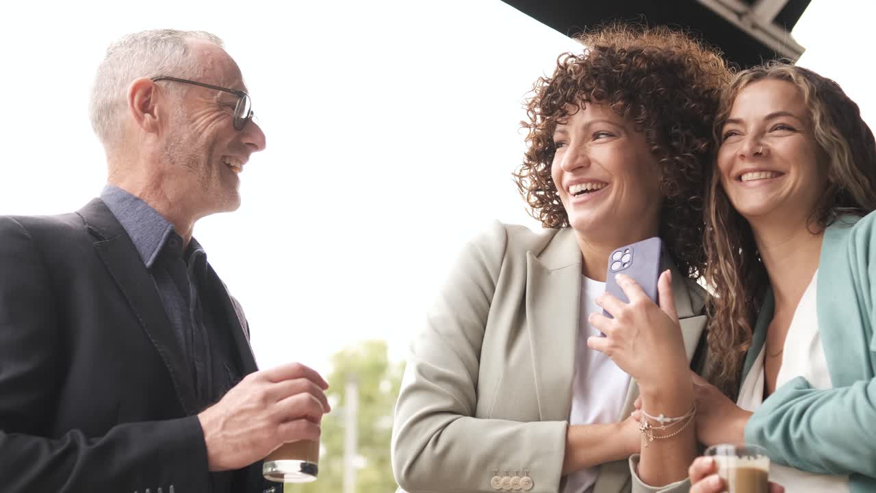 Cheerful business people using cellphone during coffee break