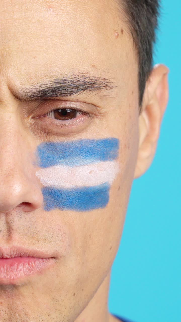 Serious man with a salvadoran flag painted on the face