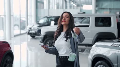 young woman scattering money in a car dealership and dancing