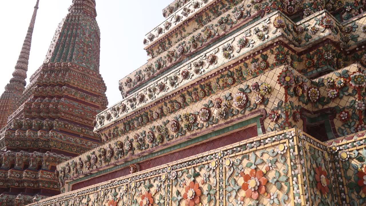 Guardando in alto verso imponenti guglie dettagliate di pagoda in un complesso di templi buddisti nella città vecchia di Rattanakosin a Bangkok, Thailandia.