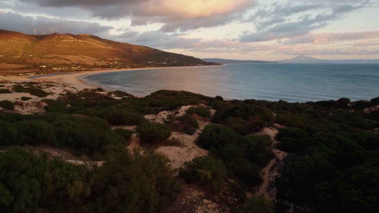 una vista de la costa de españa con la puesta de sol sobre las colinas cercanas