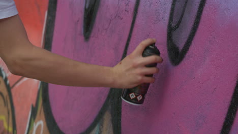 close up shot of spray paint can graffiti in action. slow motion as paint is applied to the wall.