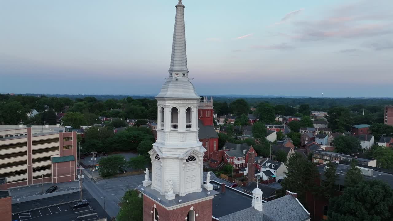 Red brick buildings and Trinity Lutheran Church in Lancaster city, Pennsylvania. Aerial forward wide shot. Sunset time in American city in summer