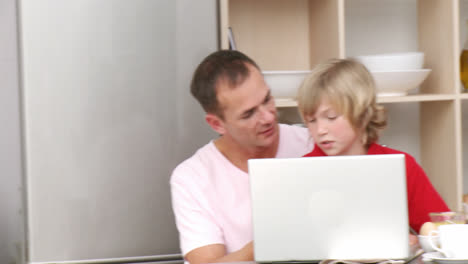 Panorama-Einer-Familie,-Die-In-Der-Küche-Frühstückt-Und-Einen-Laptop-Benutzt