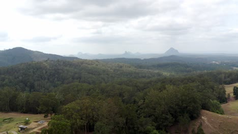 Aerial-View-Of-Dense-Forest-In-Glass-House-Mountains,-Queensland-With-Mount-Cooee-In-Far-Distance