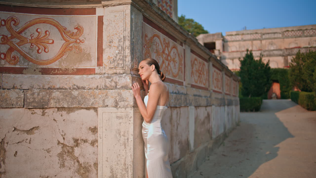 저녁에 고대 건축물을 즐기는 여성. 오래된 벽에 기대어있는 만적인 소녀