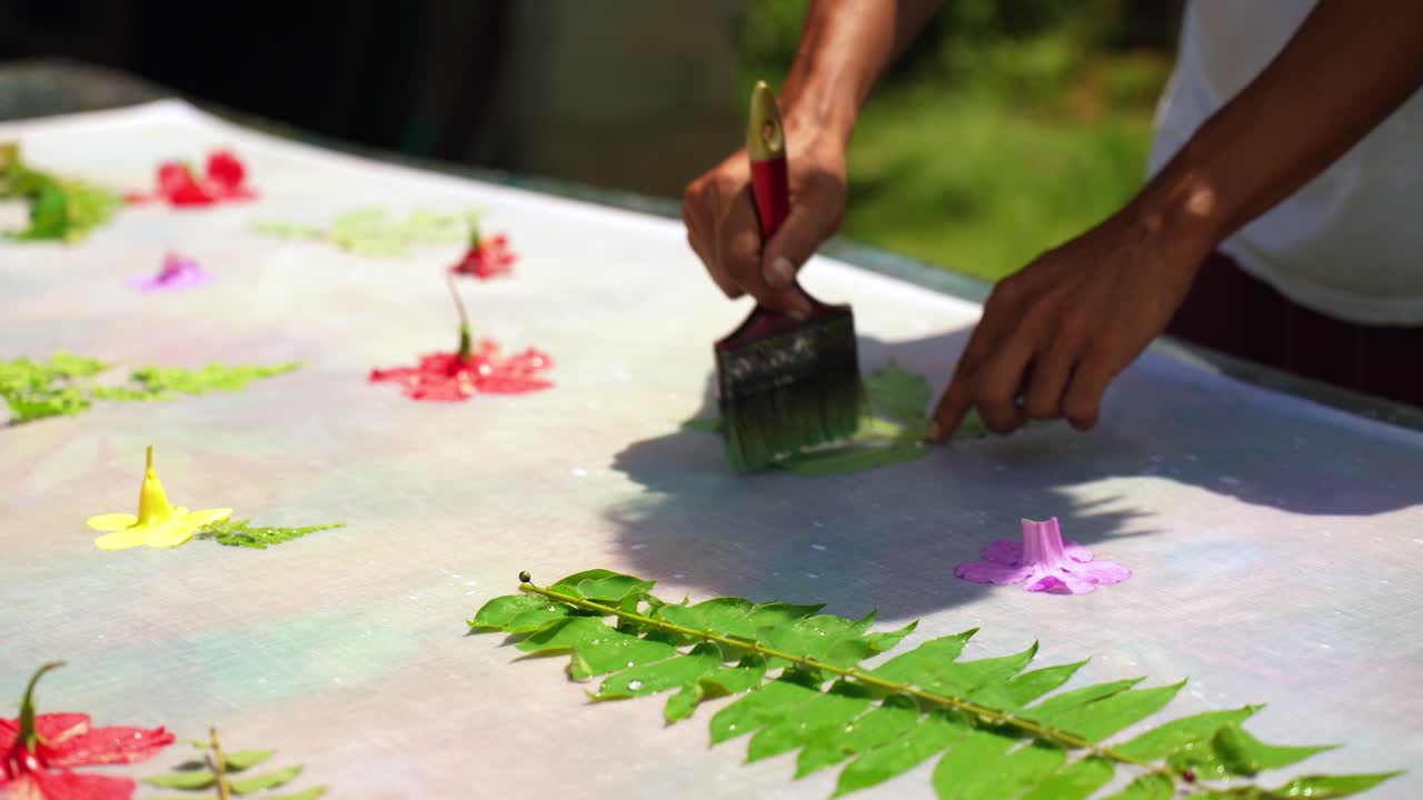 ensinando batik caseiro, sarong, pareo, homem de pele escura molhando folha verde em pano branco, mahe seychelles 25fps 3