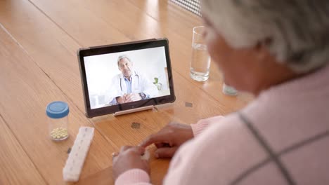 Senior-biracial-woman-using-tablet-for-medical-consultation-with-biracial-male-doctor,-slow-motion
