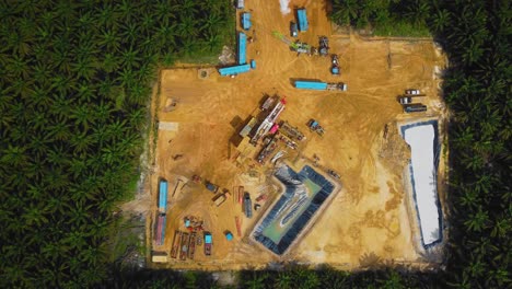 Cinematic-Drone-Footage-of-Onshore-Drilling-Rig-equipment-structure-for-oil-exploration-and-exploitation-in-the-middle-of-jungle-surrounded-by-palm-oil-trees-during-sunset-and-high-oil-price