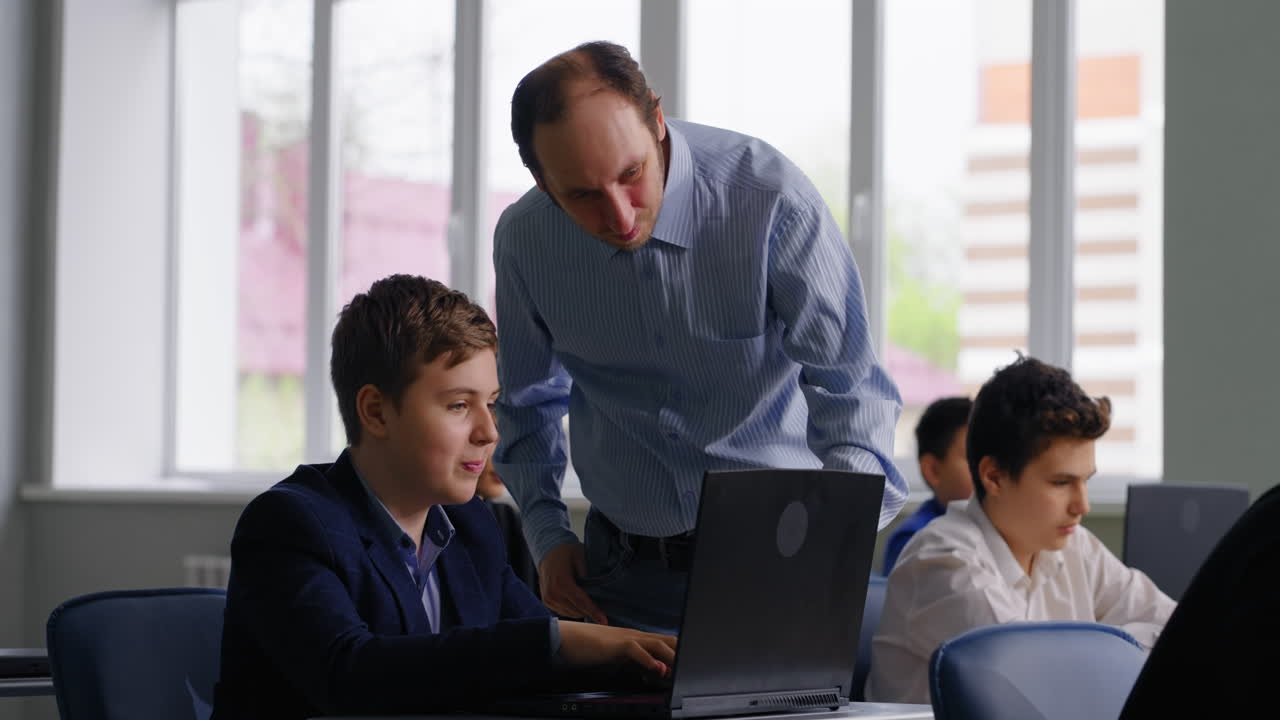 maestro ayudando al estudiante con una computadora portátil en el aula