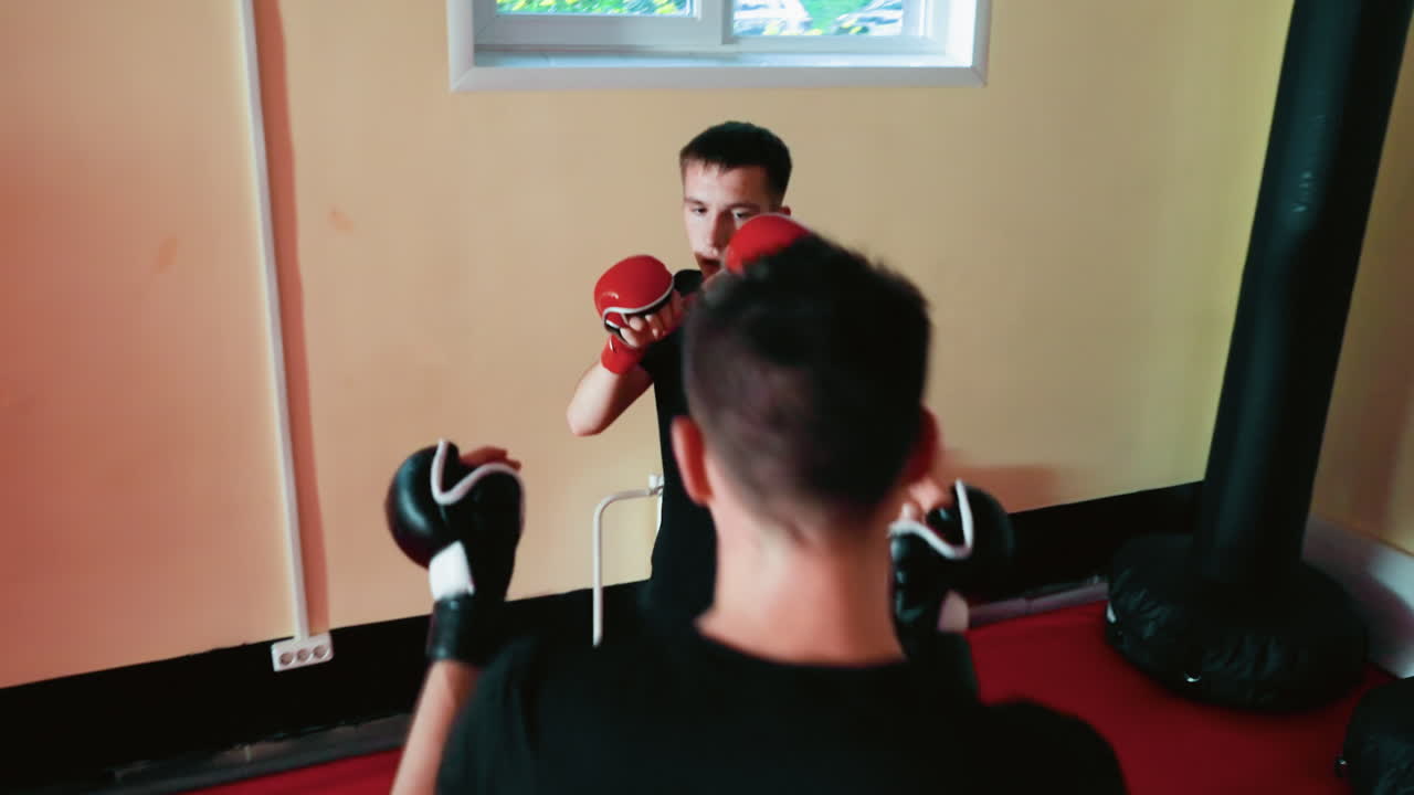 Fighters sparring in gym, young men wearing gloves practicing combat training, focused stance, concentration, showcasing martial arts technique, competitive sports spirit with intensity and energy
