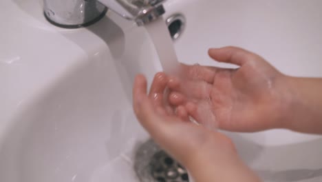 cute-girl-washes-hands-and-face-with-water-at-ceramic-sink