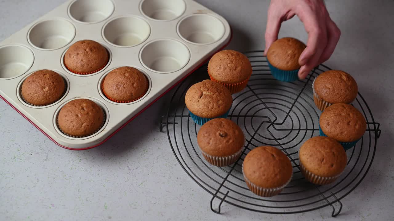 mano masculina poniendo muffins recién horneados en la bandeja de enfriamiento del pastel