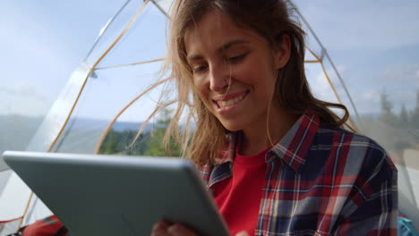 mujer leyendo un libro electrónico en una tableta digital en una tienda de campamento