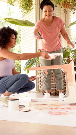 vertical video: painting furniture together, two women enjoying diy home improvement project indoors