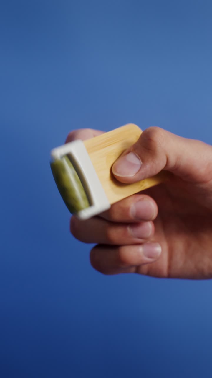 Hand holding a wooden massage roller on blue background
