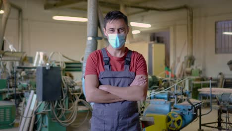 a man in a face mask and overalls stands in a workshop