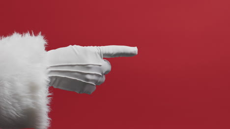 video of hand of santa claus in white glove pointing with copy space on red background
