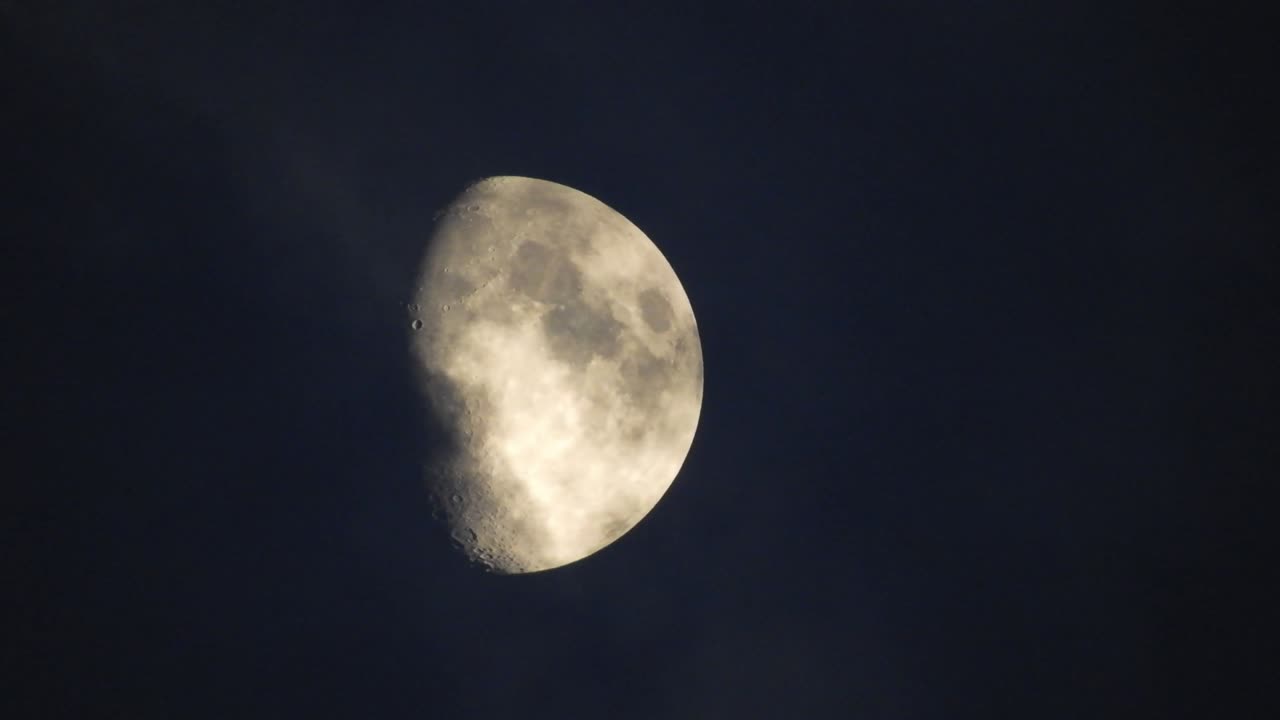 Moon at night with cloud real time. 4k video moon in the black sky.  Clouds passing by moon at night. night sky with cloudy weather