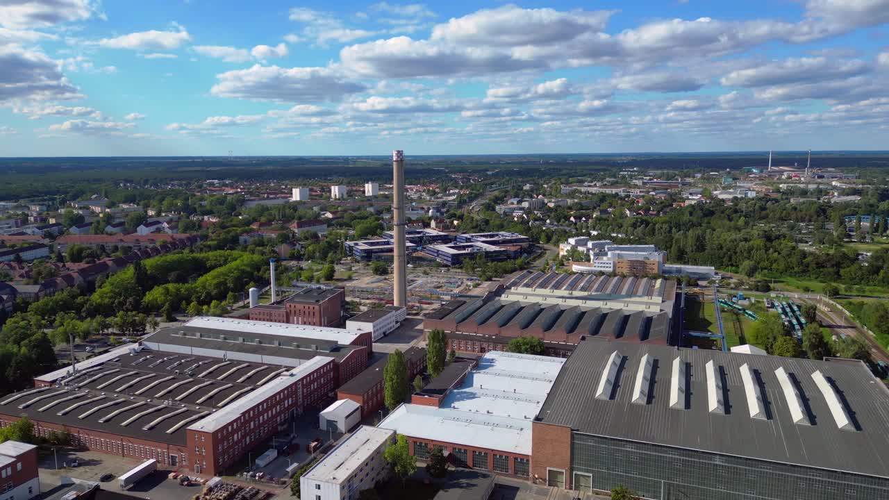 industrial buildings and a chimney in Hennigsdorf, Germany, with a train passing by. Wonderful aerial view flight overflight flyover fly push forward drone