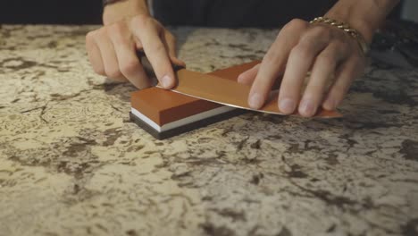 Close-Up-Of-Hands-Sharpening-Knife-Using-Fine-Stone