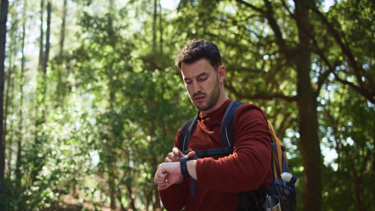 Uomo che fa escursionismo nella foresta e controlla il suo smartwatch