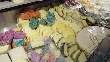 huge number of different cheeses are on display in the store. retail of gastronomic goods in the supermarket. smooth pan of camera