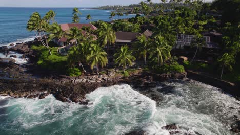 drone orbits and rises crashing against volcanic black rock spiralling upwards to reveal homes on the coast