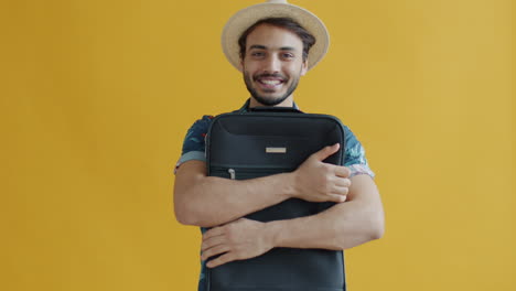man excitedly holding suitcase