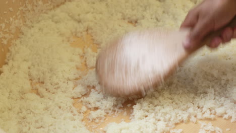 chef esparciendo arroz blanco en una palangana de madera para un plato de sushi