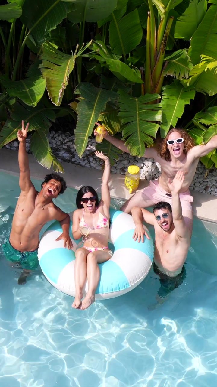 Giovani amici felici che si godono una giornata di sole in una piscina tropicale