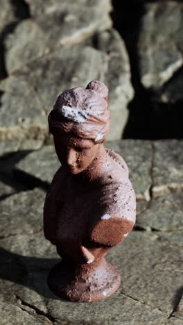 close-up of a weathered, brown bust sculpture of a woman