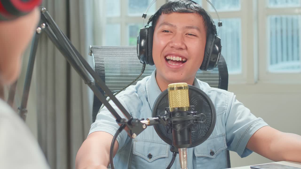 Over Shoulder View Of Asian Kid Girl Host Record Podcast Use Microphone Wear Headphone Interview Guest Conversation For Content In Her Home Studio. Content Creator Concept