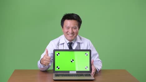 성숙한 일본인 남성, 초록색 배경의 의사