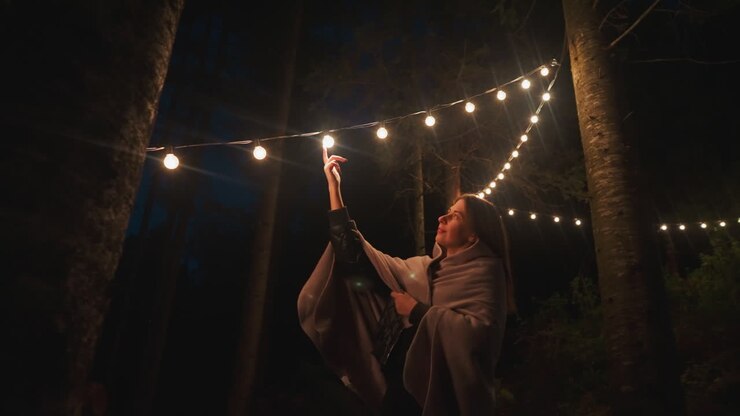 Woman puts finger on lamp in forest camp. Young woman discovers serenity in stillness and seclusion of glamping retreat immersing in fusion of repose