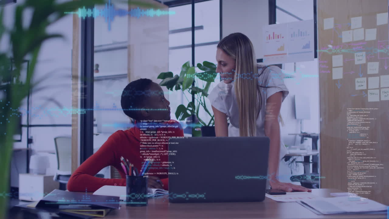 Two women collaborating at office desk with digital data overlay animation