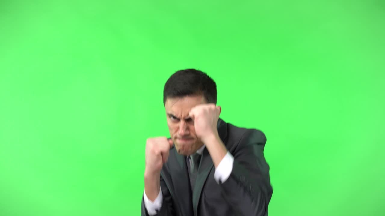 Uomo d'affari in abito che sferra pugni e si mette in posa su green screen