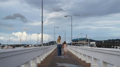 mother and daughter walk on a pier