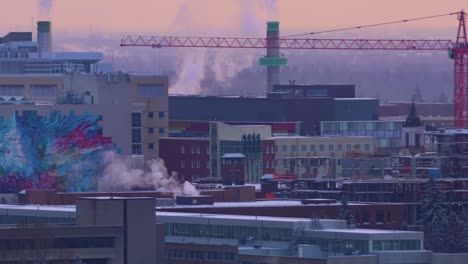 4k crepúsculo de invierno universidad de alberta edificios tejados cubiertos de nieve vapor ruidosos resoplando con árboles de bosque de fondo borroso desvanecido y algunas viviendas residenciales y grúa de construcción roja