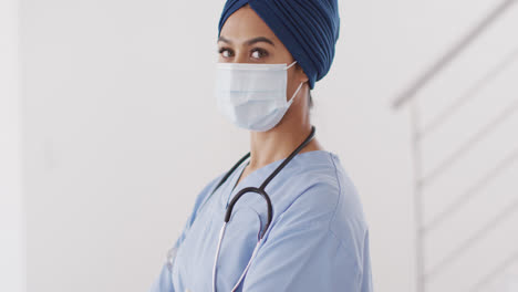 video de una doctora biracial con hijab y máscara facial mirando a la cámara