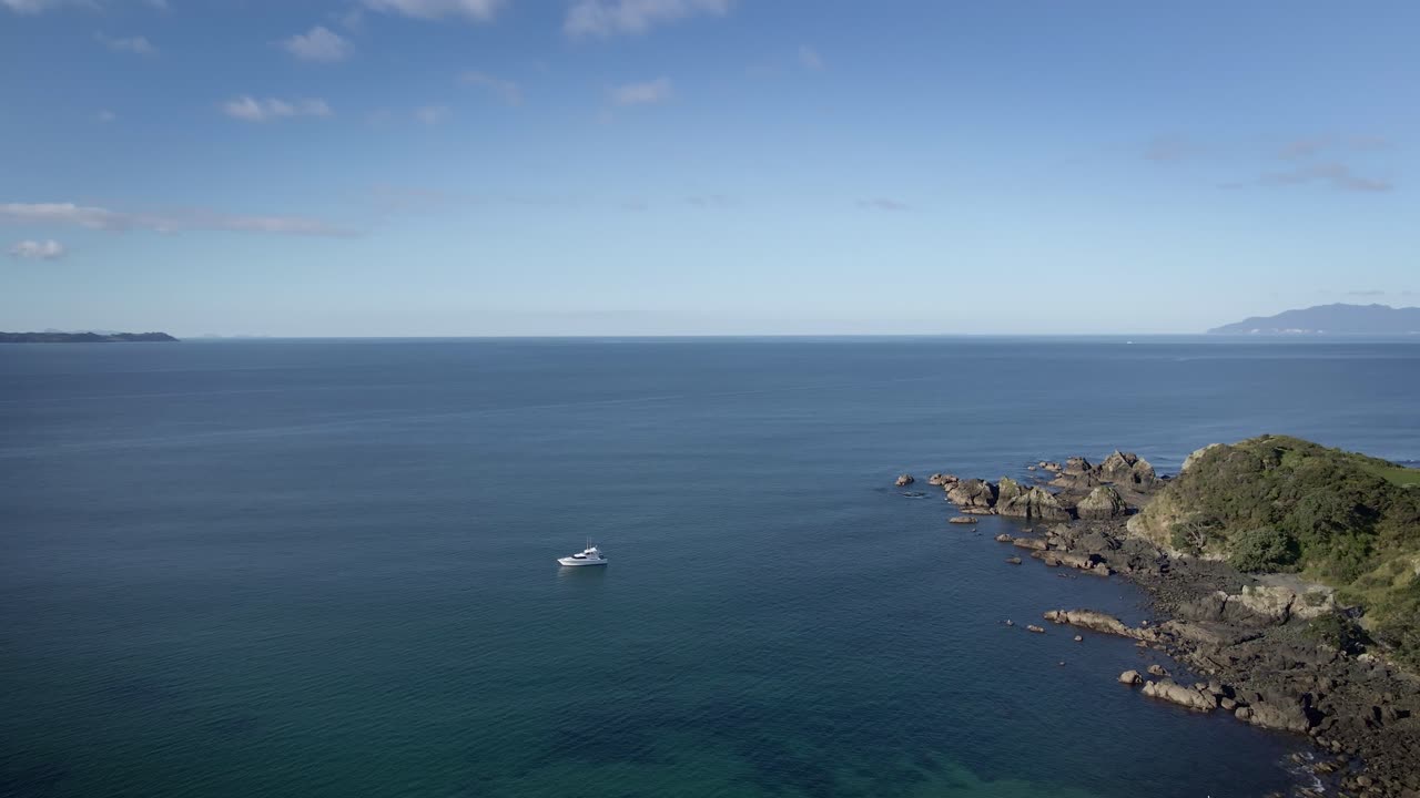 Yacht alla deriva in mare calmo e blu nella penisola di Tawharanui in Nuova Zelanda