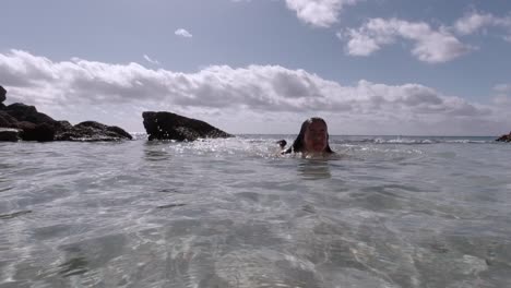 mujer caucásica nadando en una piscina de agua natural poco profunda