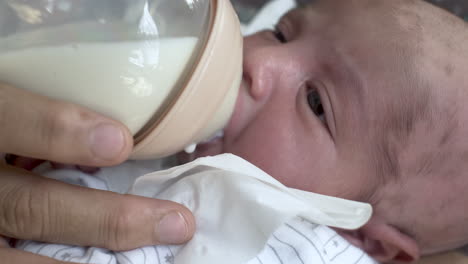 feeding newborn baby with breast milk from a bottle, close up