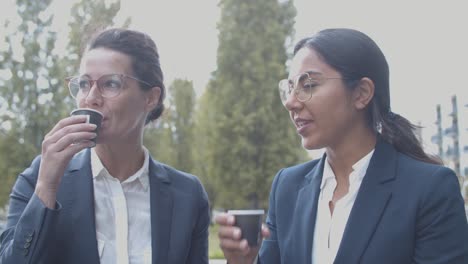 businesswomen drinking coffee and talking during break outside