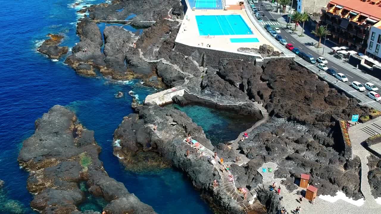 Aerial drone footage of the natural pools of Garachico Caletón. Blue ocean and the natural pools functioning as playas at Tenerife. Nice waves hit the rocks in the water.
