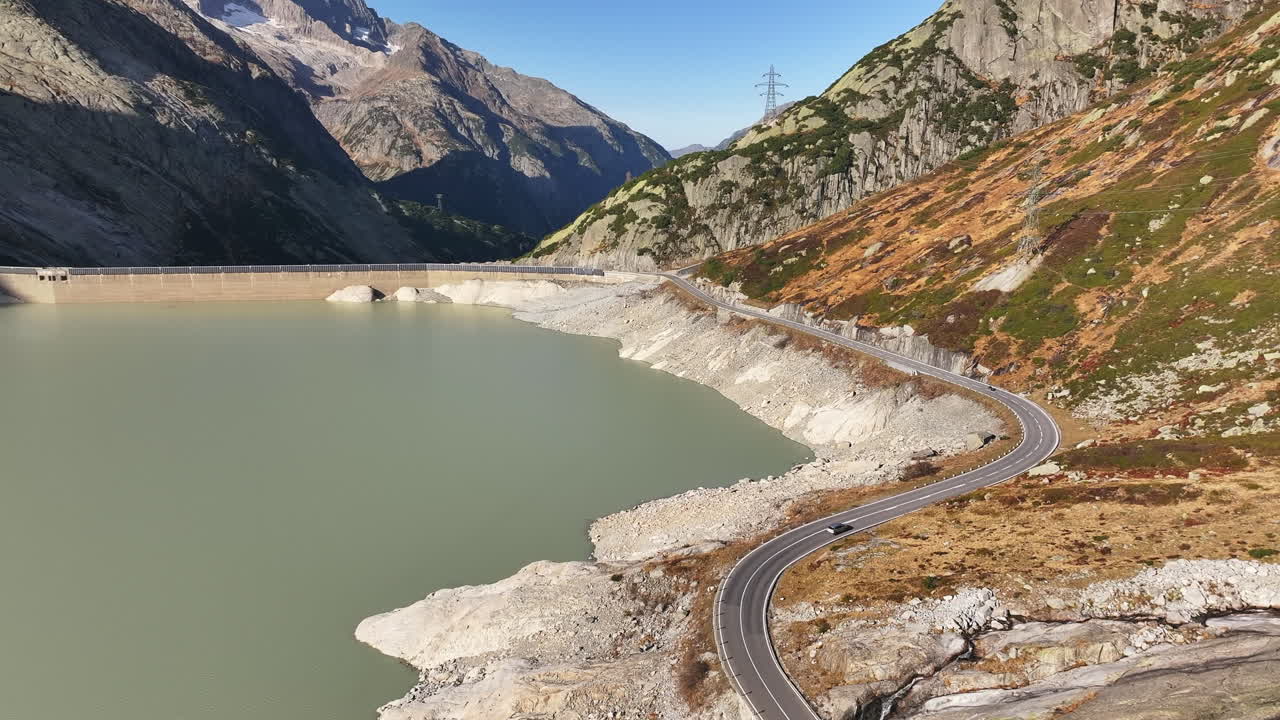 Grimsel Pass mountain road winding by a water reservoir surrounded by rocky alpine landscape